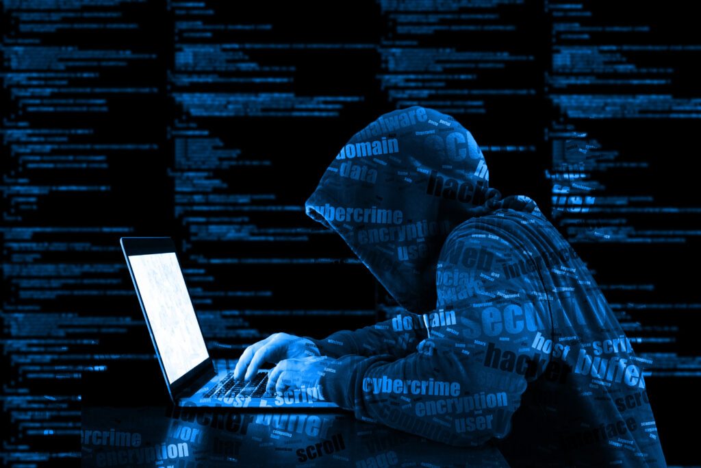 Hacker in a blue hoody standing in front of a code background with binary streams and information security terms cybersecurity concept
